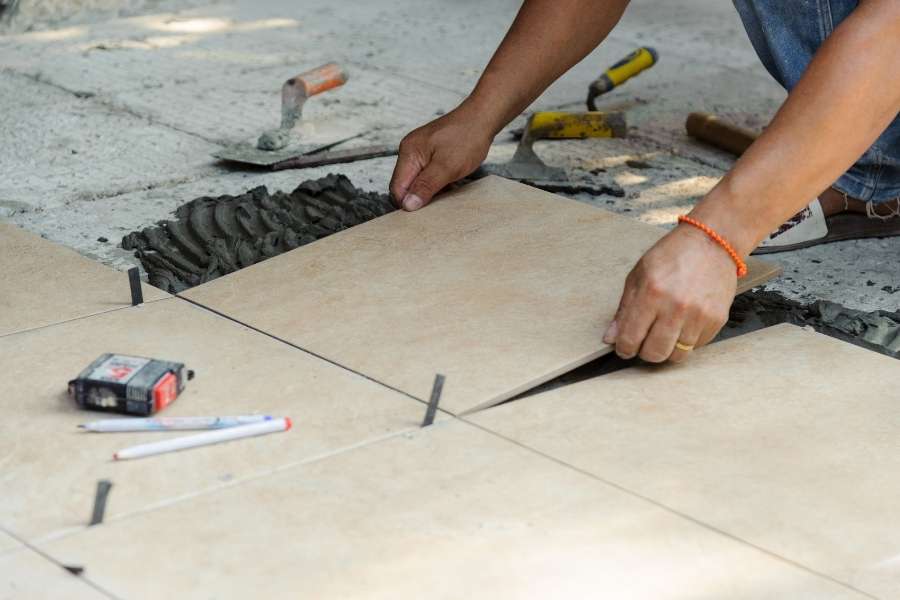 Pose de carrelage de sol avec des carreaux en céramique lors de travaux d’aménagement