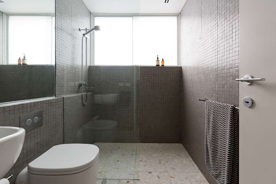 Une douche à l'italienne moderne avec parois en verre et carrelage gris dans une salle de bain épurée.