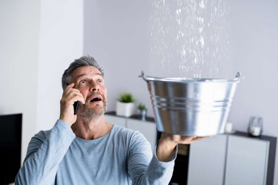 Un homme inquiet téléphone pour une fuite d'eau au plafond.