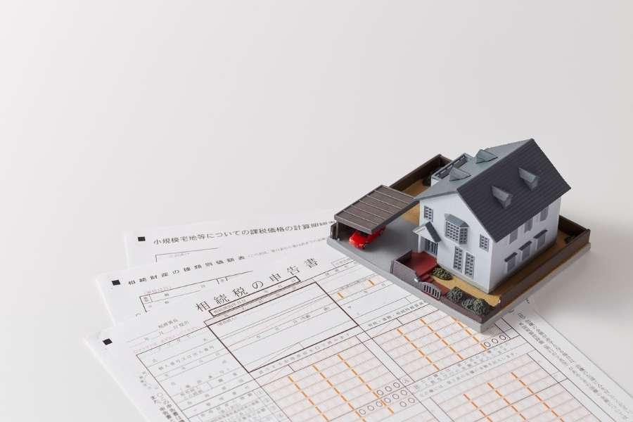 Une maquette de maison posée sur des documents officiels pour une estimation d’un bien
